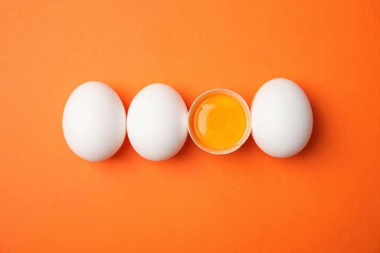 Raw chicken eggs on color background