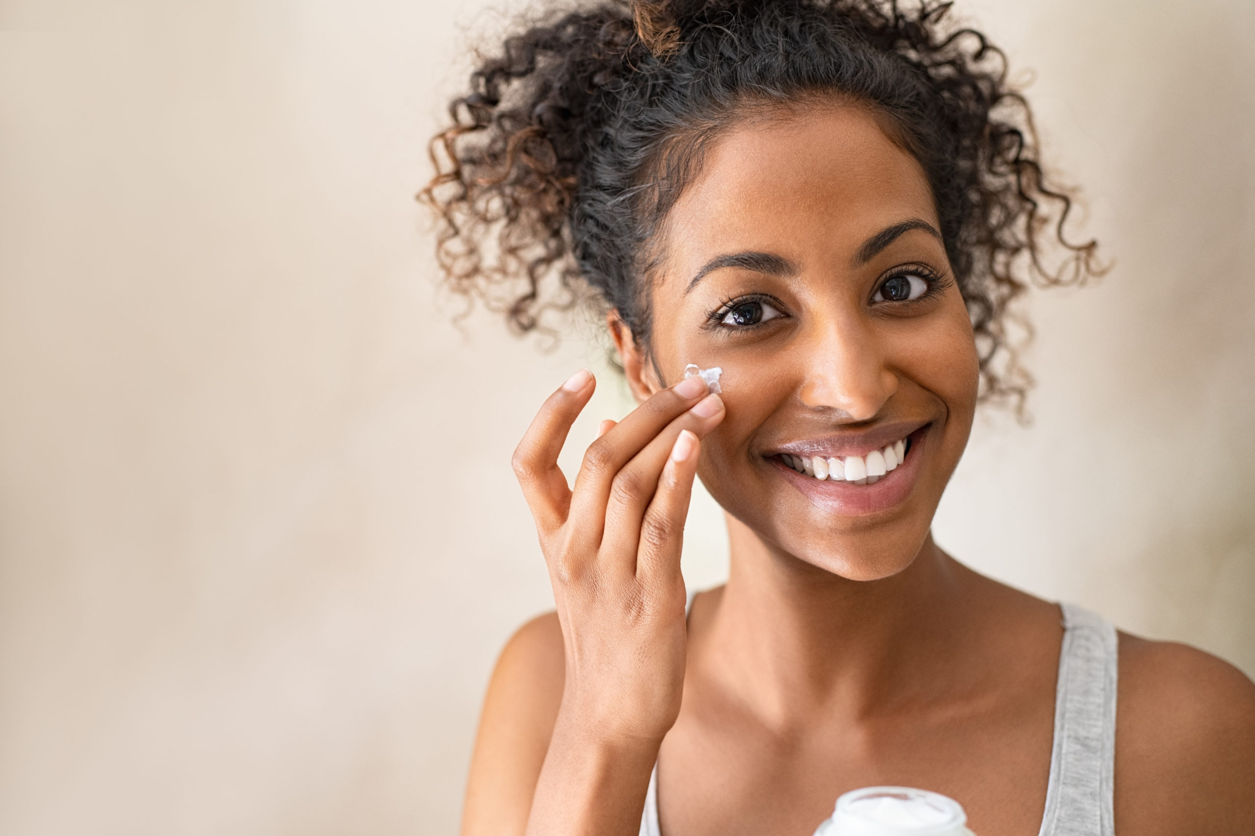 Smiling woman putting on face cream