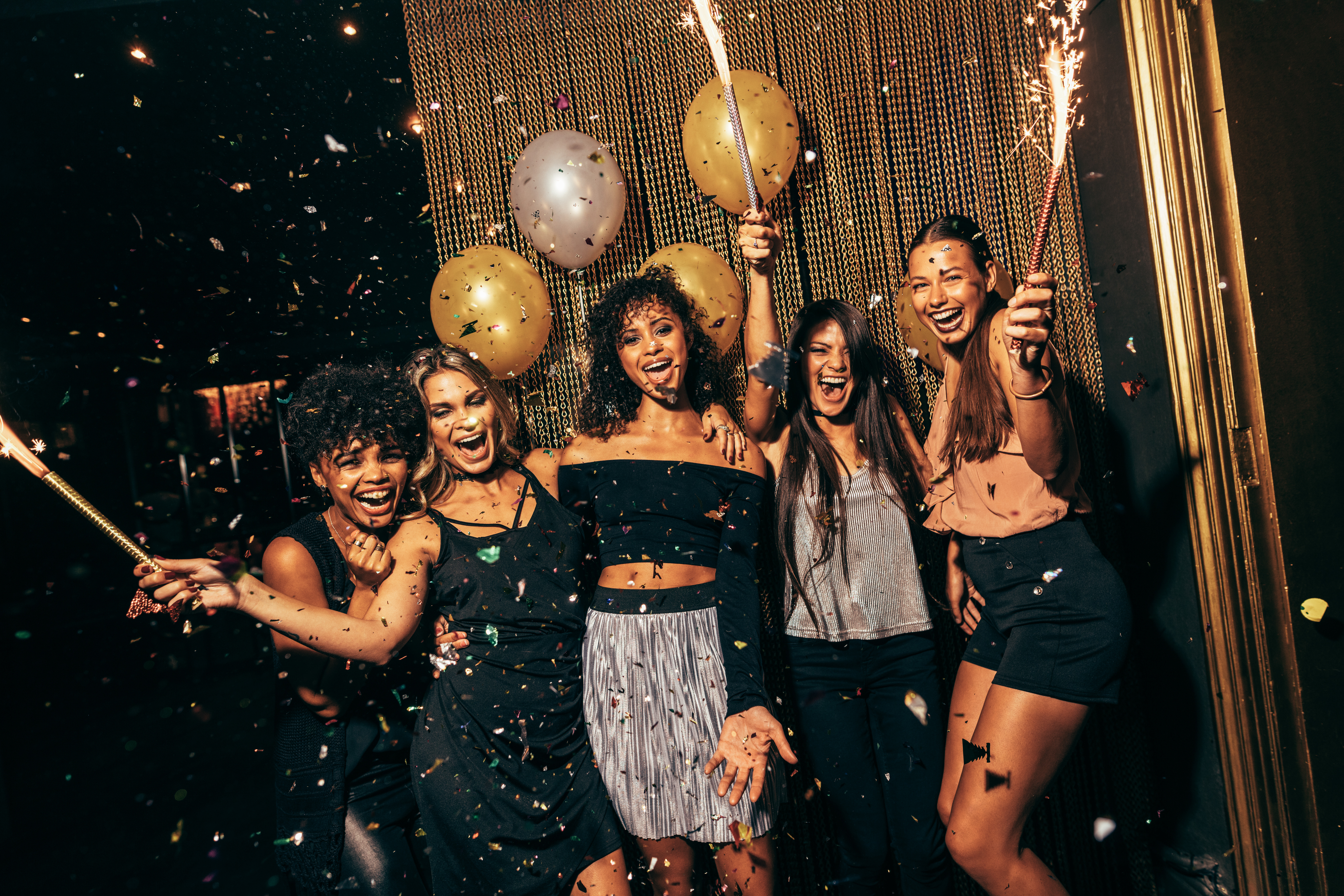 Group of ladies celebrating in club scene with sparklers